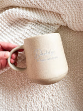 Load image into Gallery viewer, Beige ceramic mug with &#39;Daddy&#39; engraving held by a hand against a textured beige background
